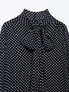 Detailed view of polka dot shirt with high collar and elegant bow tie neckline