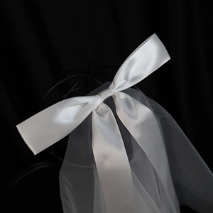 Detail of white satin bow and sheer tulle bridal veil on black vintage display stand