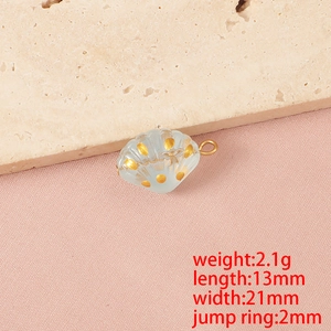 Dettaglio macro di un ciondolo a conchiglia in vetro con pois dorati, charm oceano 21x13mm DIY