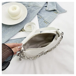 Detail of white crocodile texture crossbody bag with silver chain and zipper compartment
