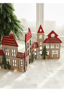 Macro detail of wooden Christmas house and snowman ornaments on snowy white base