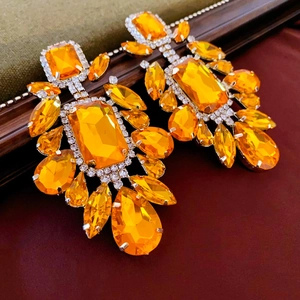 Dettaglio di grandi orecchini a goccia color ambra con cristalli e micro-pavé di diamanti