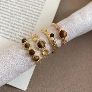 Detail of vintage gold-plated rings set featuring brown tiger eye stone and textured bands
