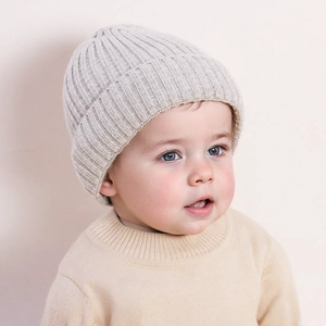 Close-up of soft knit texture on baby winter hat and beige ribbed pullover sweater