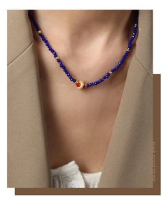 Close-up of beaded necklace with faceted navy stones and gold accents on model