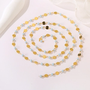 Detailed macro of gold metal discs and light blue beads chain on white background