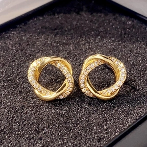 Macro view of gold intertwined rings earrings with pavé-set shimmering zircon stones