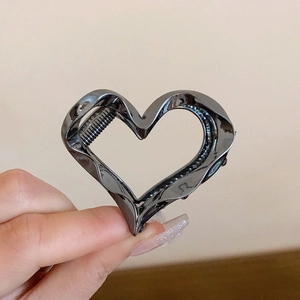 Close-up of a dark grey metal hair claw clip featuring a unique hollow heart shape