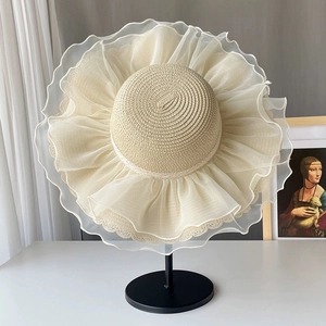 Detail of a beige straw sun hat with large wavy organza brim and fine weave texture