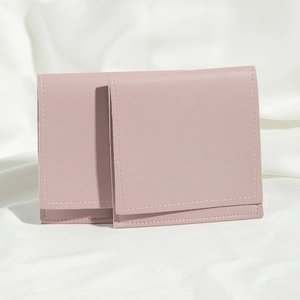 Close-up of pink textured PU leather pouches with flap closure on white fabric