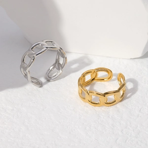 Detail shot of minimalist gold and silver chain link rings on a marble stone base