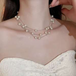 Close-up of elegant multi-layer pearl necklace on model showing silver chain detail