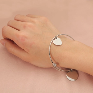 Polished stainless steel adjustable bangle with heart and round charms on pink silk