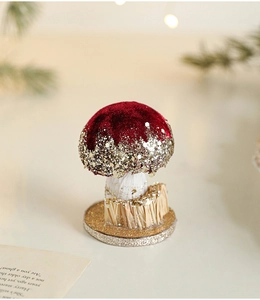 Macro view of burgundy velvet mushroom decor with gold glitter and pine needle accents