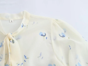 Dettaglio della camicetta in chiffon a fiori con scollo a fiocco ed etichetta taglia S