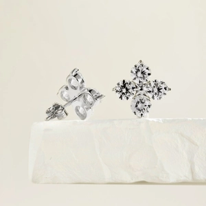 Macro shot of silver four-leaf clover earrings with sparkling cubic zirconia on stone