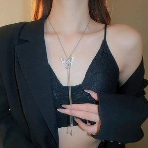 Detail of silver butterfly pendant necklace with long tassel chains on a fashion model
