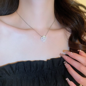 Close-up of a silver four-leaf clover pendant necklace with shimmering zircon gemstones