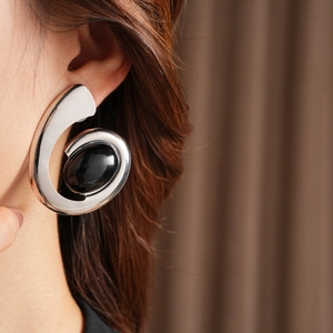 Close-up of vintage silver swirl earrings with black oval gemstone on a model