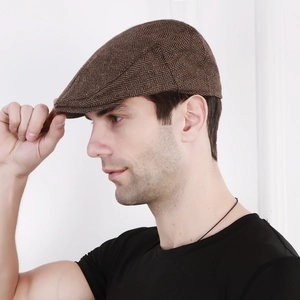 Side profile of a man wearing a brown herringbone flat cap for sun protection