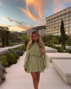 Nahaufnahme grüner Chiffon-Rüschen an einem Minikleid, getragen auf einer Resort-Terrasse