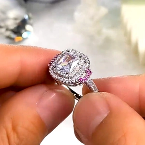 Macro detail of silver ring with emerald-cut main stone and pink side gemstones