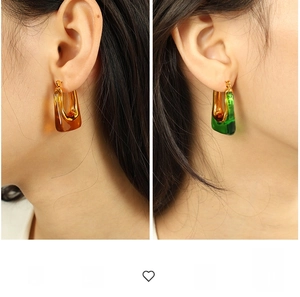 Detail of U-shaped chunky earrings featuring amber and green resin with gold plating