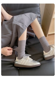 Detail showing grey mesh calf socks with metallic sneakers in a stylish sitting pose