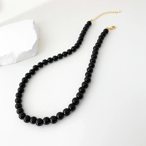 Detailed view of black onyx beaded necklace with gold lobster clasp and extension chain