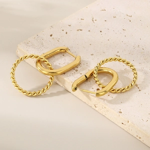 Golden twist hoop earrings with geometric U-shape link on a textured stone surface