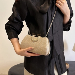 Elegant gold glitter box clutch bag with metallic chain strap held by a model