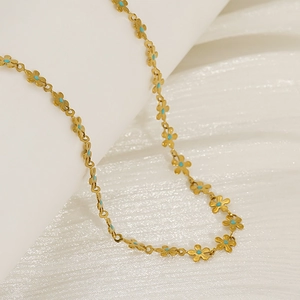 Elegante collana in titanio dorato con ciondoli a fiore e dettagli in blu turchese