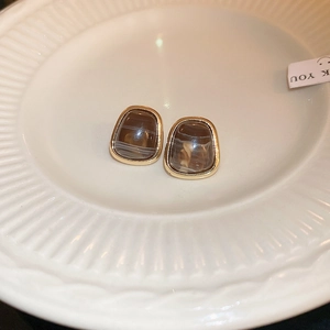 Macro detail of trapezoid resin earrings with marble texture and gold metal border