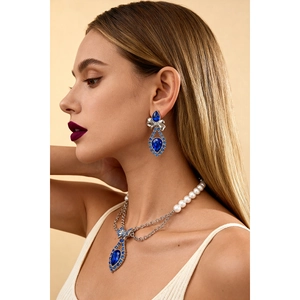 Elegant silver necklace with blue teardrop gemstones, pearls, and bow detailing