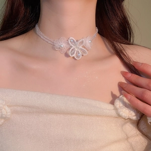 Detailed close-up of beaded flower necklace with pearls worn on neck for women