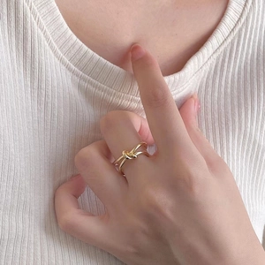 Detail of 18K gold plated stainless steel knot ring worn on hand with minimalist design