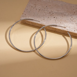 Macro shot of large silver geometric round earrings on a decorative stone base