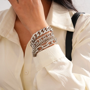 Detail of layered silver Cuban and textured link chains worn on wrist with white shirt