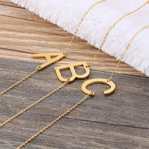 Elegant gold stainless steel letter A B C pendant necklaces on a luxury white fur surface