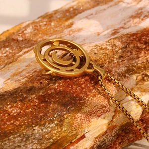 Macro shot of 18K gold plated compass pendant with moon and sun patterns on a rock
