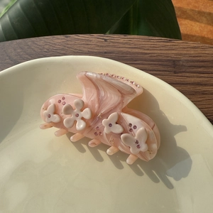 Gros plan sur pince à cheveux fleur rose avec strass sur assiette en céramique