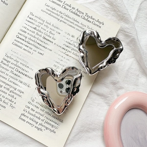 Close-up of heart-shaped silver earrings with unique lava texture on a magazine page