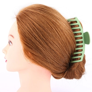 Macro side view of a large matte light green hair claw clip on a woman's hair bun