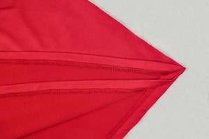 Detail of red knit dress showing double-needle hem stitching and fine fabric texture