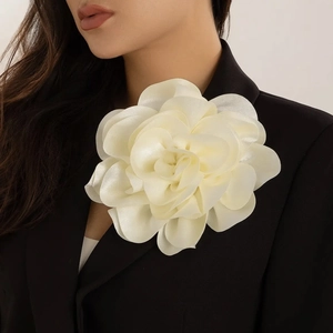 Macro detail of a large cream fabric rose flower brooch pinned on a black blazer