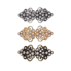 Detailed macro view of vintage rhinestone sweater clips in silver, gold, and bronze finishes