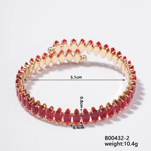 Detailed close-up of golden diamond-shaped open bracelet with marquise red zircons