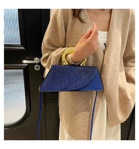 Blue crocodile pattern crossbody bag featuring a unique gold sculpted handle and strap