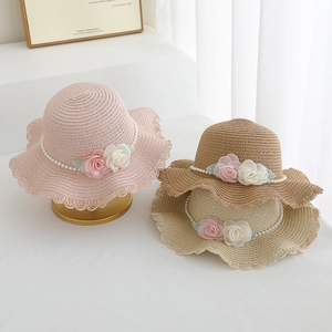 Detailed view of straw sun hats with lace trim, pearl chains, and floral accents