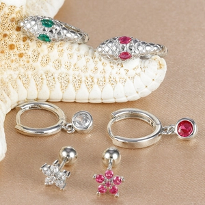 Detail view of silver snake-shaped earrings and flower studs with colorful zircons